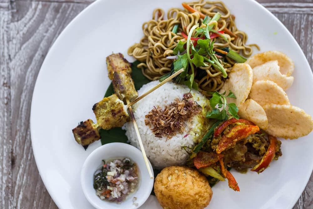 An assortment of Balinese cuisine displayed on a plate, featuring vibrant colors and diverse flavors.